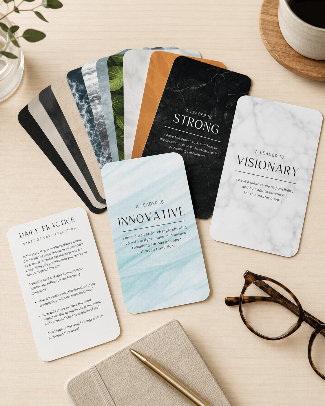 A fanned spread of Leader Cards on a desk beside a notebook, glasses and coffee